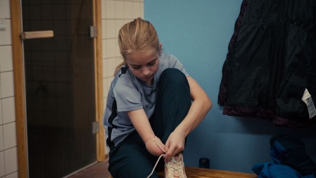 Celina bindet sich mit ihrem amputierten Arm die Schuhe zu