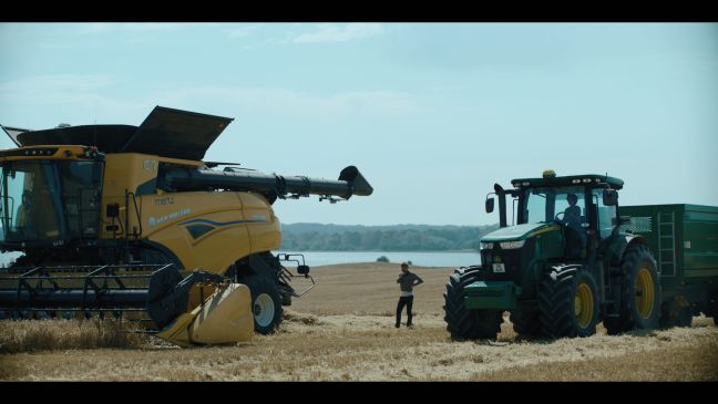 Traktor und Mähdrescher stehen auf dem Feld, dazwischen Erik beim Telefonieren