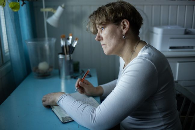 Anu schreibt in Notizbuch und guckt aus dem Fenster