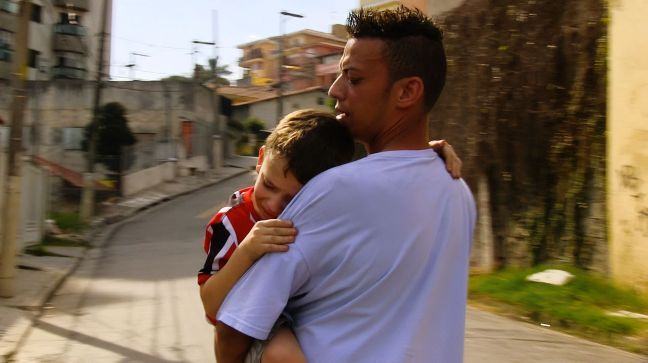 Vater läuft mit Sohn auf dem Arm durch die Straßen