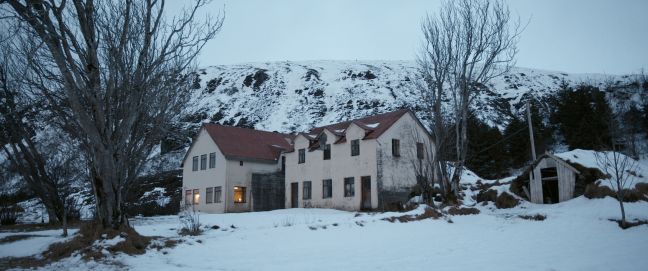 ein Haus, Schnee im Vordergrund, Berge im Hintergrund