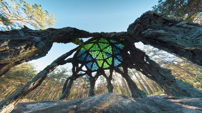 Ein Kunstwerk im Wald, eine Kuppel aus Holz mit farbigem Glas als Dach