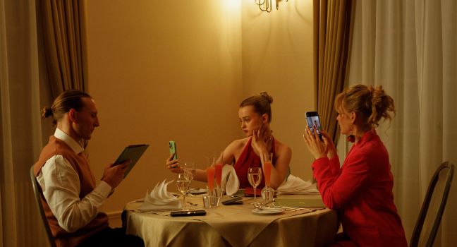 Luca posierend mit ihren Eltern am Esstisch, jeder ein mobiles Endgerät in der Hand