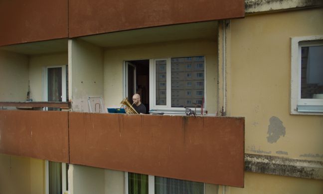 Mann spielt Instrument auf Balkon