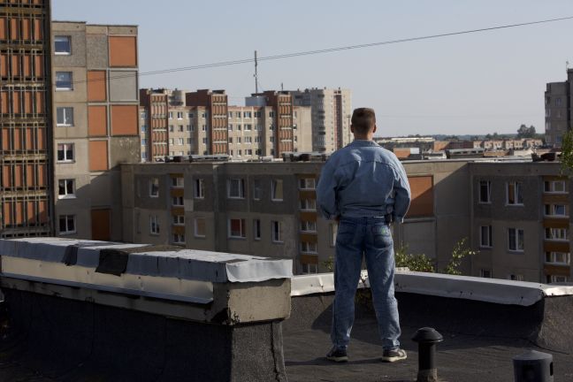 Junger Mann in Jeans blickt über die Dächer der Stadt