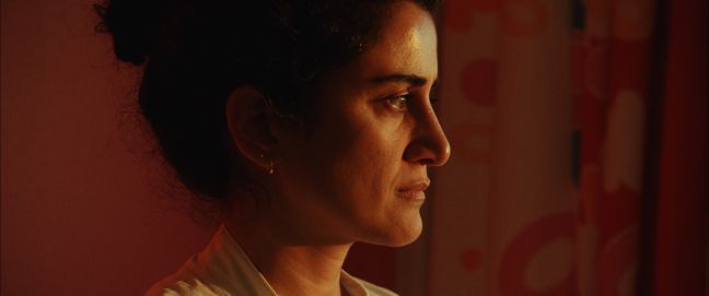 Alex guckt angestrengt, sie ist rot angeleuchtet