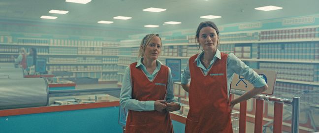 zwei Frauen in roten Schürzen in einem Supermarkt