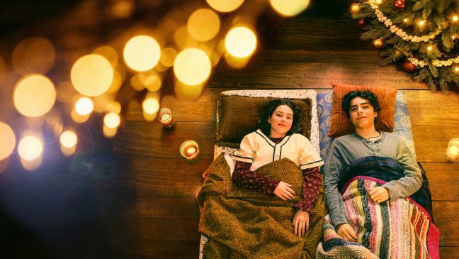 Martha und Enes liegen auf dem Boden, in der Ecke steht ein Weihnachtsbaum