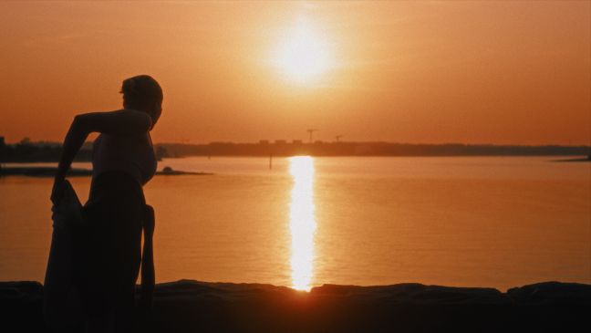 Silhouette einer Frau bei Sonnenuntergang am Wasser