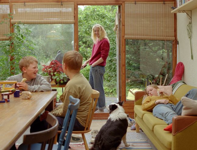 Anna/Mutter grillt, Kinder chillen im Haus, Hund sitzt auf dem Boden