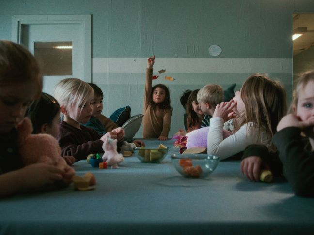 Mädchen meldet sich an einem Tisch voller Kinder