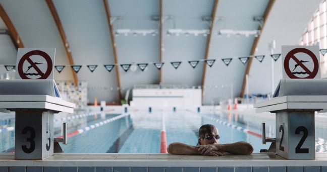 Schwimmer:in mit Schwimmbrille am Beckenrand