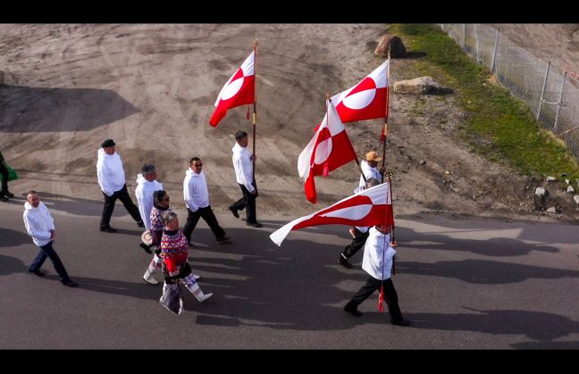 Menschen gehen durch die Stadt mit grönländischen Flaggen